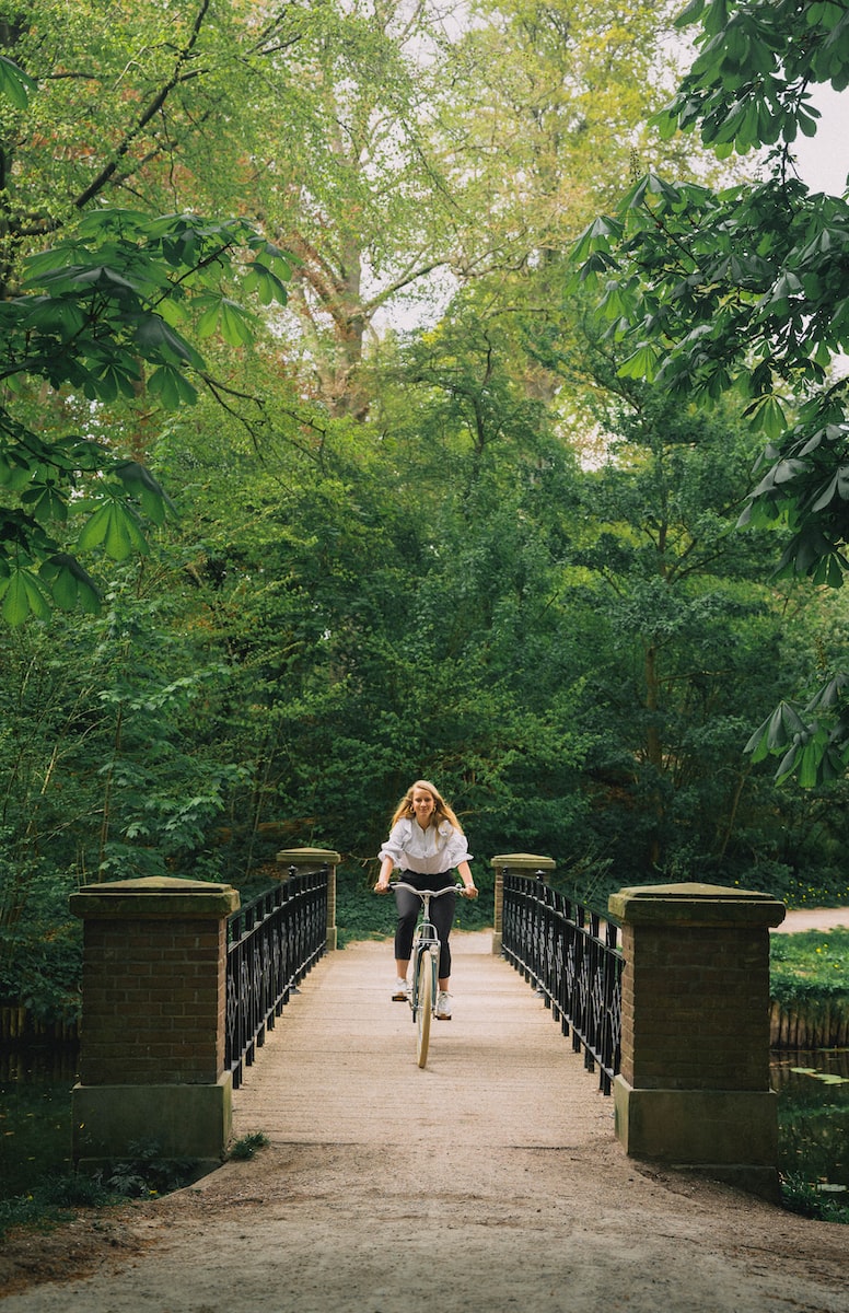 a woman riding a bike across a bridge